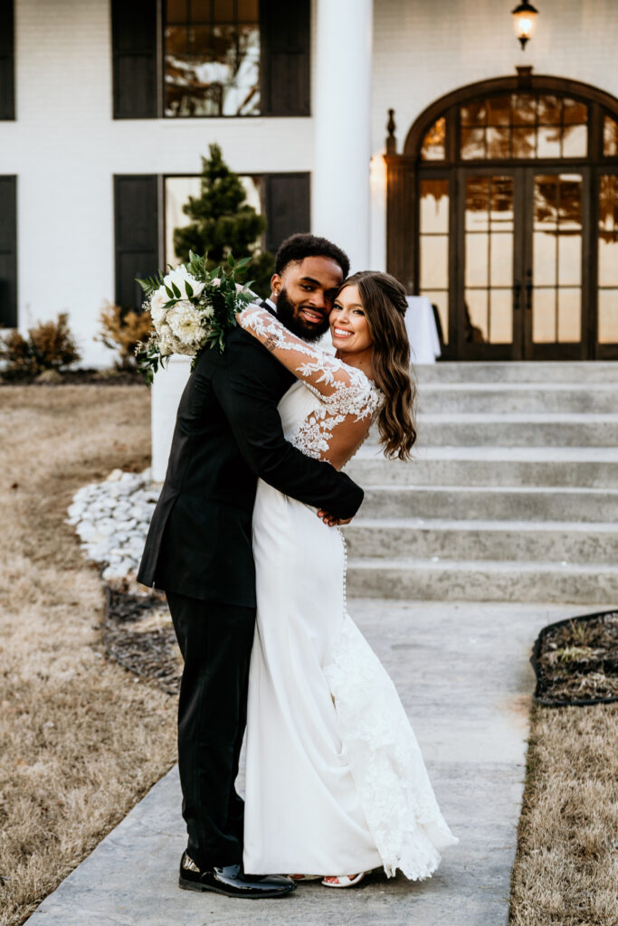 Bride and groom share a hug in front of their beautiful venue