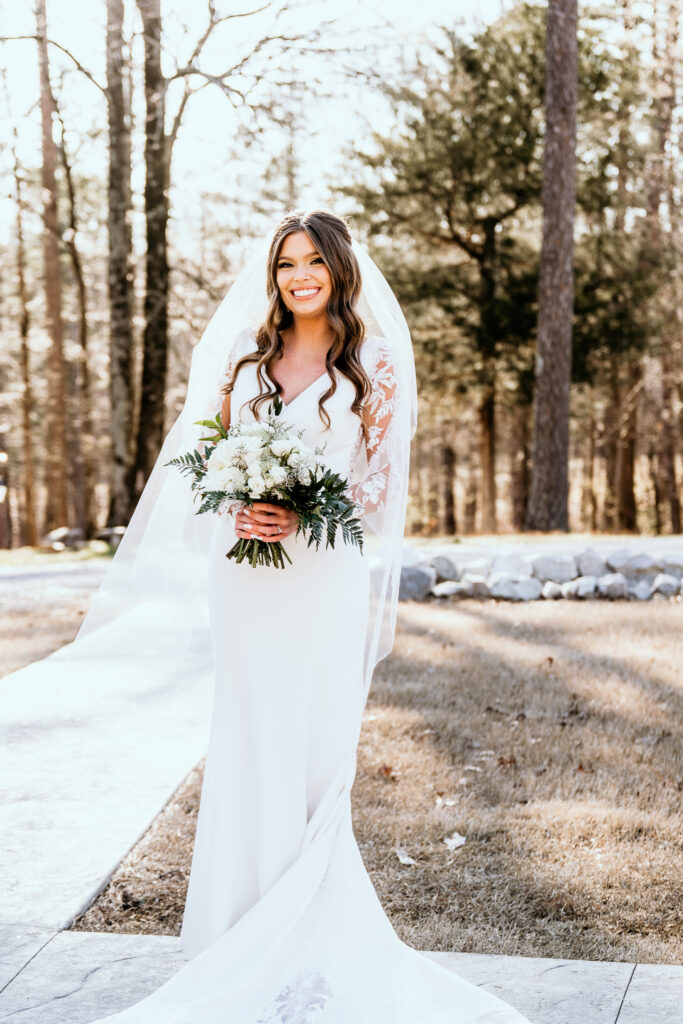 Bridal portrait of the bride holding her bouquet and wearing her veil while backlit by the glow of the sun