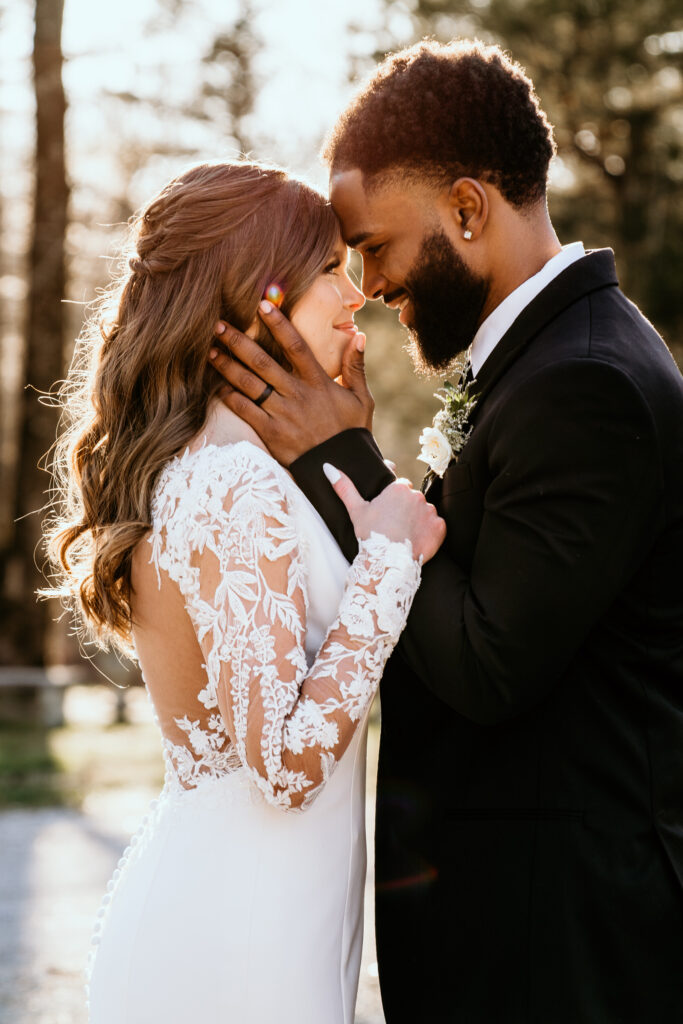 Groom holding the brides face close to his while looking into her eyes lit by the glow of sunset