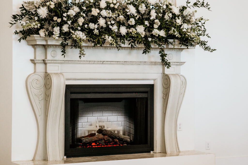 Large electric fireplace decorated with a large white floral mantle piece