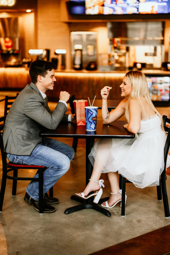 couple enjoying snacks and a soda at the movie theatre for their engagement session