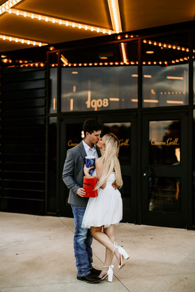 Couple kissing outside the theatre with the lights on 